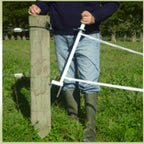 USA Grazing Systems Taragate multi-strand electric fence gate being operated by a farmer in a pasture